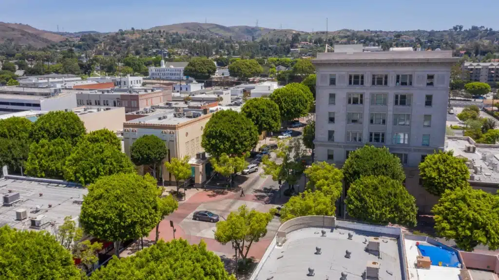 Tree-lined downtown area with buildings and hills in the background.