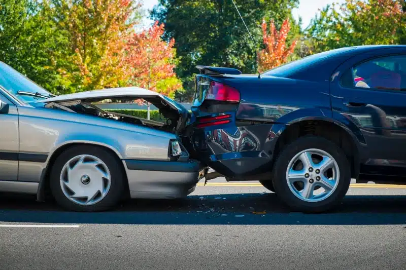 Rear-end car collision with visible vehicle damage on road.