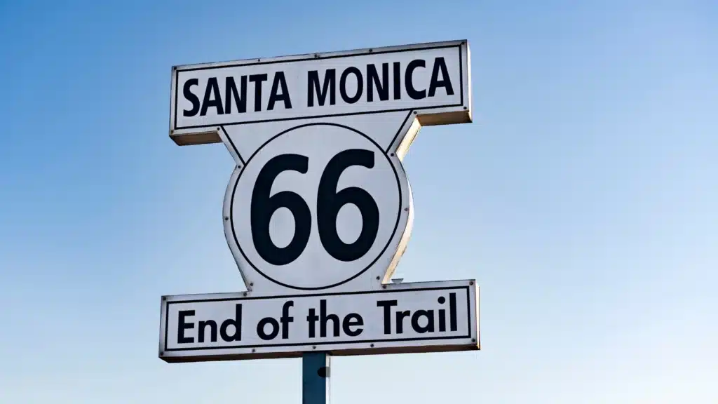 Route 66 end-of-the-trail sign in Santa Monica against a clear blue sky.