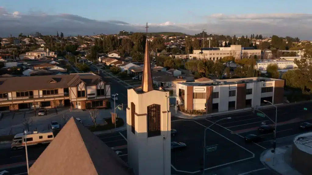 Aerial view of a church steeple at a neighborhood intersection during golden hour.