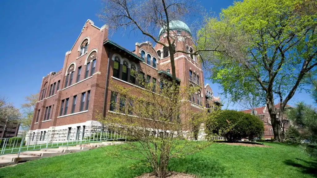 Historic red-brick building with a domed tower and green lawn.